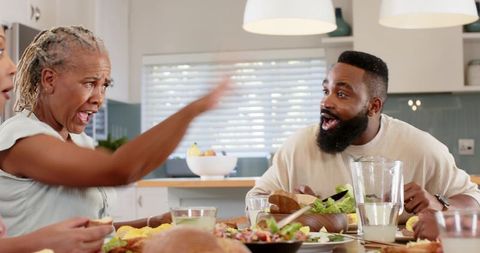 Multigenerational african american family enjoying lively meal with surprised reaction at table