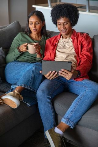 Interracial Couple Relaxing on Sofa, Embracing Technology