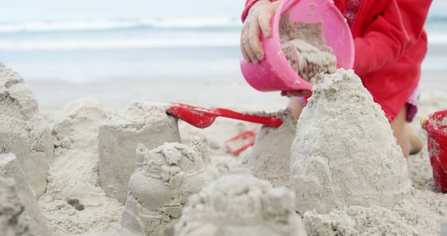 Child Building Sandcastle at Beach with Red Bucket - Download Free Stock Images Pikwizard.com