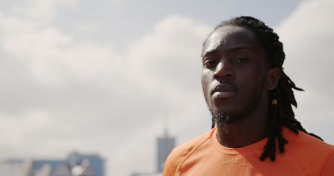 Focused Athlete Poses Outdoors in Bright Orange Jersey under Clear Sky