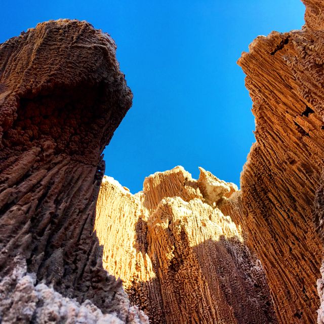This image shows striking eroded rock formations under a clear blue sky. The unique textures and shades of the rock create a captivating and dynamic landscape. Perfect for use in travel websites, geology or natural landscapes presentations, brochures, or as a compelling addition to natural phenomena collections.