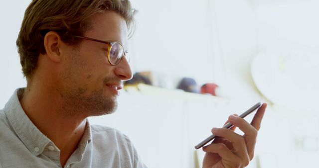 Young Man Using Smartphone for Voice Command in Bright Room - Download Free Stock Images Pikwizard.com