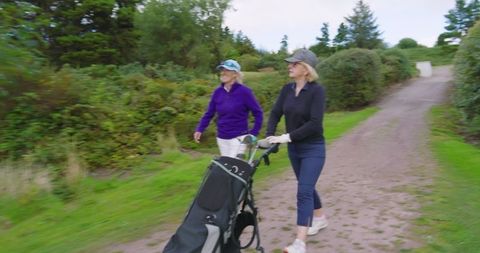 Senior Women Enjoying Leisurely Golf Day Pushing Carts