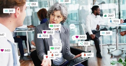 Mature businesswoman leading collaborative meeting with tablet and social notifications