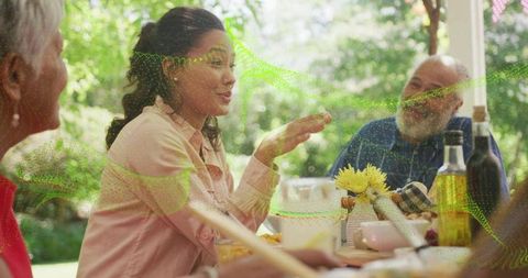 Multigenerational family sharing outdoor lunch on shaded porch with wooden table