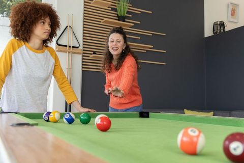 Diverse friends playing billiards in modern recreation room, casual indoor leisure