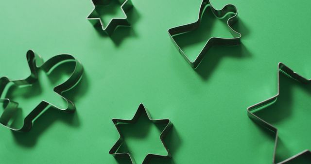 Angel, gingerbread man and star shaped cookie cutters and copy space on green background. christmas, tradition and celebration concept image.