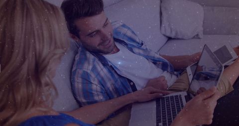 Couple Relaxing on Couch Engaged with Laptop Indoors