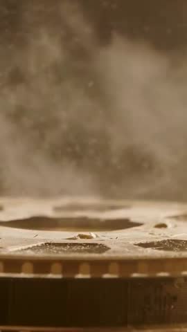 Vertical close-up of boiling pan releasing steam and golden droplets over gas burner