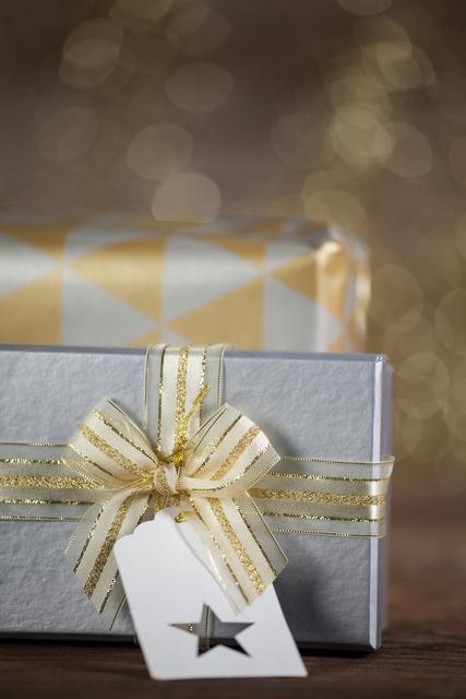 Close-up of wrapped gift box with tag on wooden table during christmas time