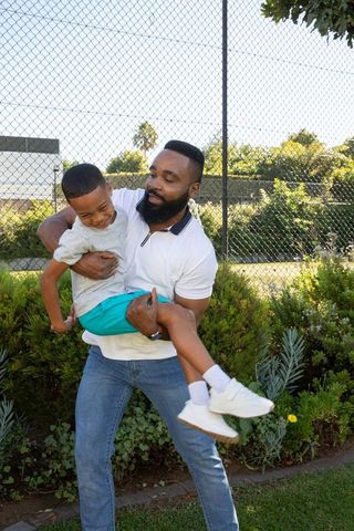 Cheerful father lifting son in outdoor fall adventure