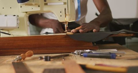 African American Craftsman Sewing Leather in Workshop