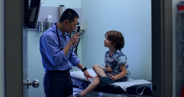 Healthcare professional conducting routine medical examination for young boy in clinical setting. Suggests pediatric healthcare, regular checkup, children's medical services, doctor-patient interaction, medical consultation, preventive medicine. Perfect for health insurance, pediatric care advert, clinic promotional materials.