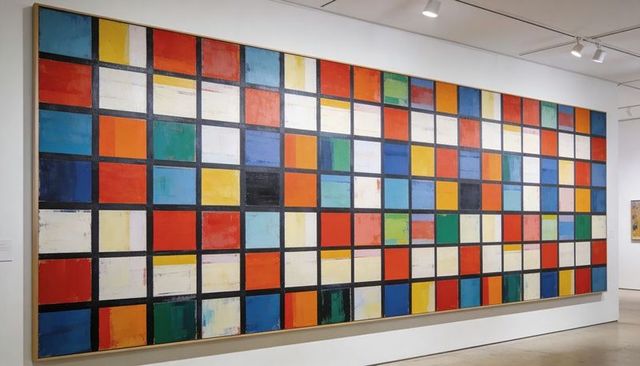 Displaying large abstract geometric grid painting on gallery wall with bold color blocks