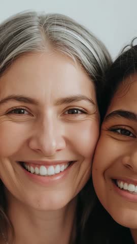 Vertical video: Mother and daughter pressing cheeks, smiling, blinking in tender close-up