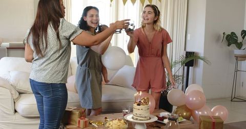 Friends Celebrating Birthday with Champagne Toast in Cozy Living Room