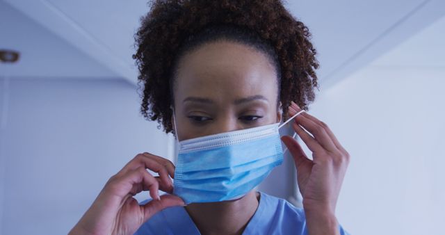 Portrait of biracial female doctor putting face mask on. medicine, health and healthcare services during coronavirus covid 19 pandemic.