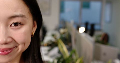 Smiling asian woman in modern open-plan office workplace