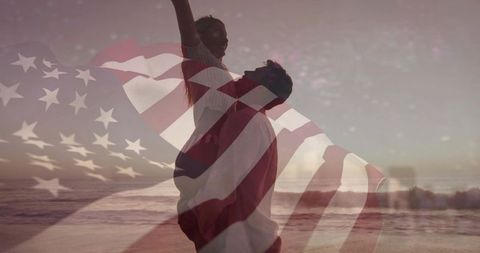 Silhouetted couple embracing on beach at sunset with american flag double exposure