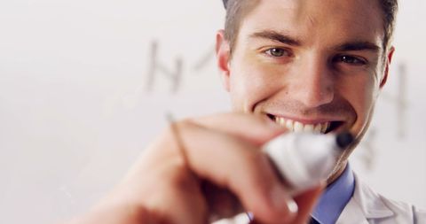 Man smiling while writing with marker