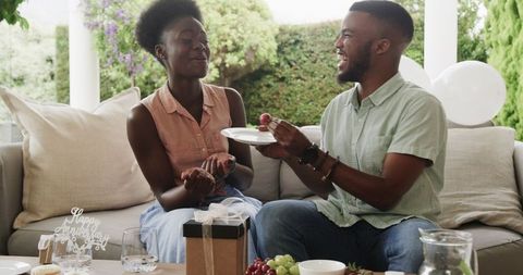 Couple celebrating anniversary exchanging gifts on patio