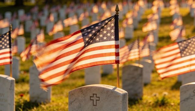 American flags waving over military headstones at sunrise honoring fallen veterans