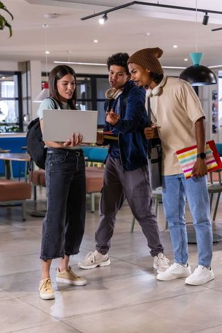 Diverse students collaborating on laptop in modern campus lounge studying and planning