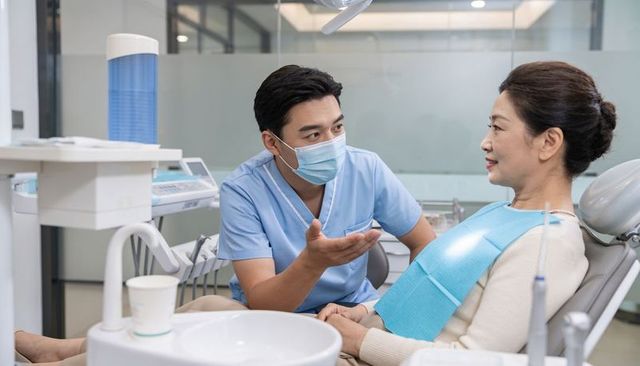 Dentist consulting senior woman patient in modern dental clinic during examination