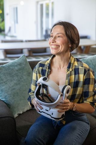 Smiling Woman Holding VR Headset in Living Room