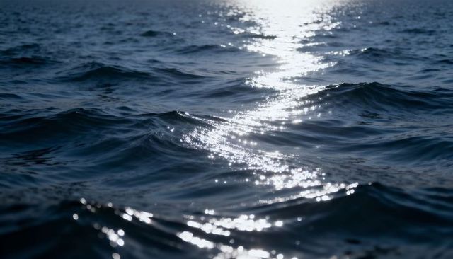 Shimmering ocean surface reflecting sunlight with gentle waves, deep blue calm