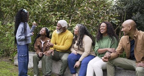Multigenerational Family Enjoying Relaxed Outdoor Gathering on Log Bench in Garden