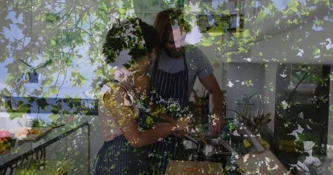 Couple cooking together in modern kitchen with leafy double exposure and intimate moment