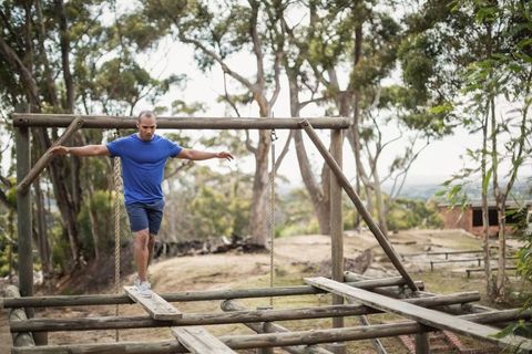 Man balancing on outdoor rope and log obstacle course
