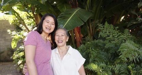 Asian Mother and Daughter Smiling Together in Lush Greenery