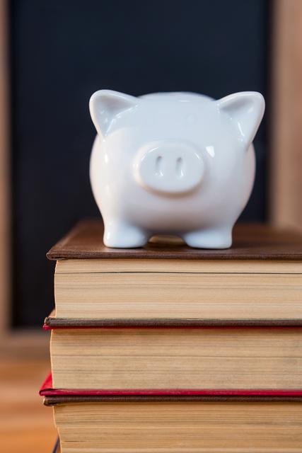 Close-up of books stack with a piggy bank on a table