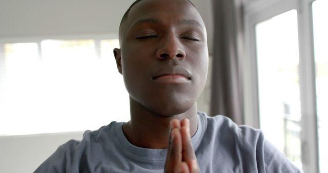 Young Man Meditating with Hands Pressed Together in Quiet Room - Download Free Stock Images Pikwizard.com