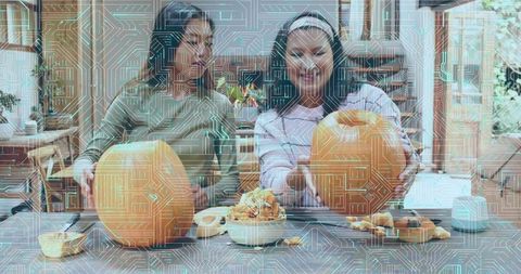 Mother and daughter carving pumpkins on kitchen island, smiling, sharing autumn moments