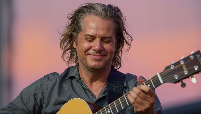 Smiling Guitarist Performing Outdoors at Sunset