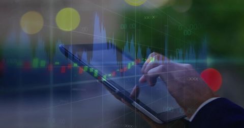 Business analyst tapping tablet and swiping candlestick charts at dusk for mobile trading