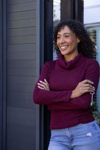 Young Woman Celebrating New Homeownership Near Entrance