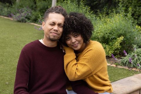 African american couple embracing on backyard lawn wearing knit sweaters