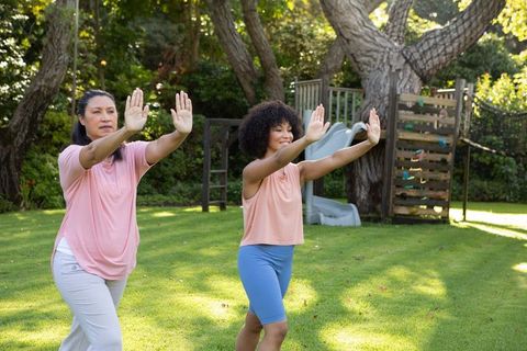 Mother and Daughter Practice Balance Exercise in Outdoor Garden Setting