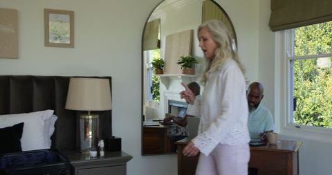 Woman Packing Suitcase While Man Works Remotely on Laptop