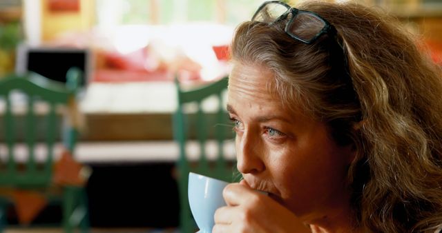 Woman with Curly Hair Enjoying Hot Beverage in Cozy Cafe - Download Free Stock Images Pikwizard.com