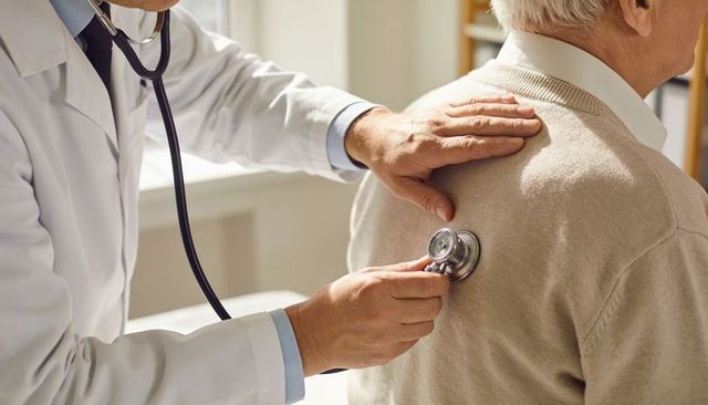 Physician auscultating elderly patient with stethoscope during routine checkup