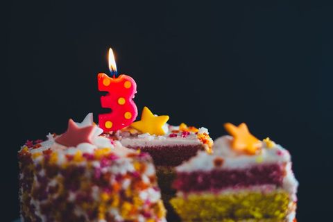 Colorful Birthday Cake with Lit Candle and Star Decorations