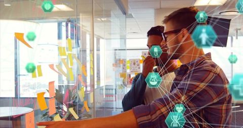 Collaborative team planning at glass wall with Post-its and tech network overlay