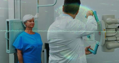 Technician assisting elderly woman in x-ray room