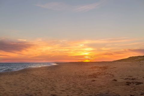 Golden Sunset Over Empty Sandy Beach With Gentle Waves and Coastal Dunes