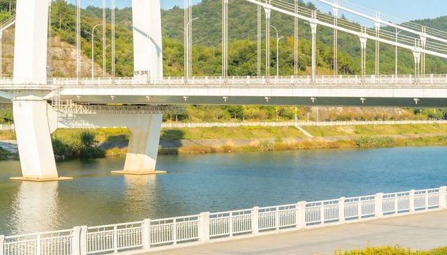Spanning White Suspension Bridge over Serene River with Riverside Promenade Railings